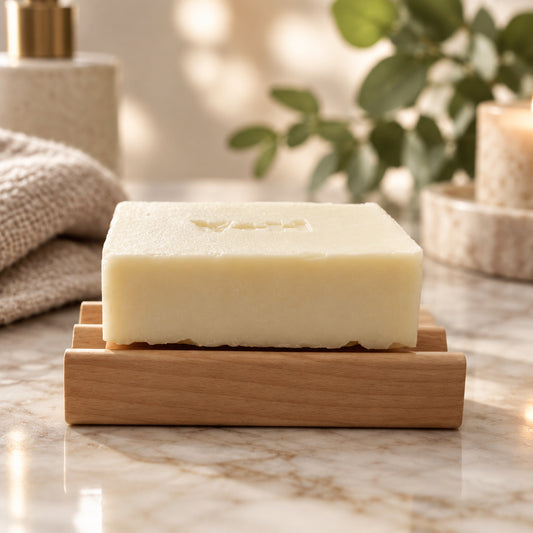 A bar of artisan soap resting on a Valor+Harvest American Red Alder natural wood soap dish.