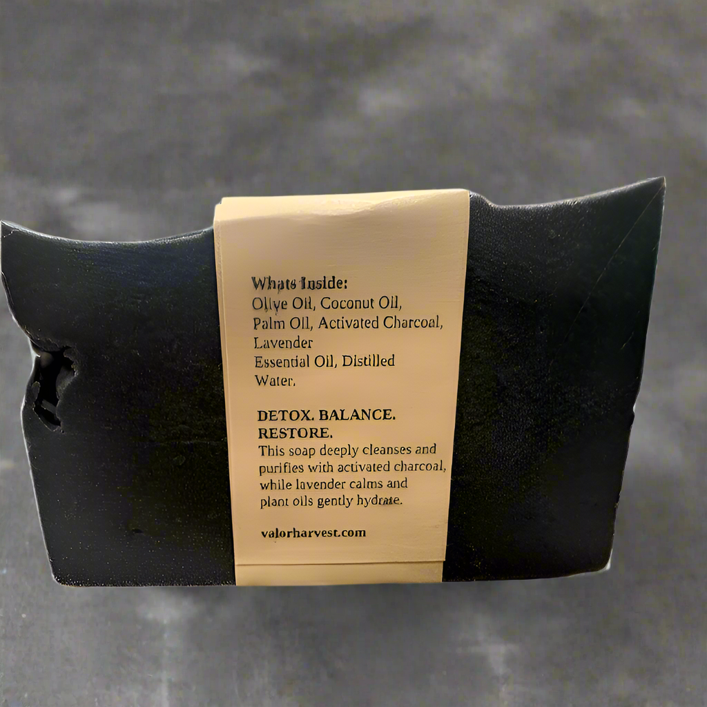 Back view of Charcoal Activated Natural Soap showing ingredients like coconut oil, shea butter, activated charcoal, and essential oils on label.