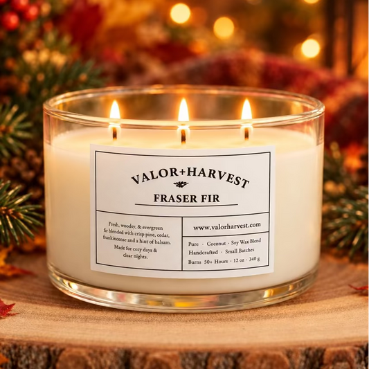 Lit Valor+Harvest Fraser Fir 12 oz soy wax candle in a glass jar on a rustic wooden base.