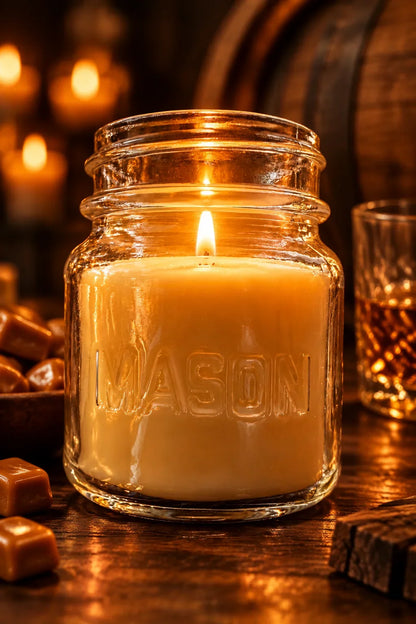 Lit Butterscotch & Bourbon soy coconut wax candle in a Mason jar with caramels and bourbon.