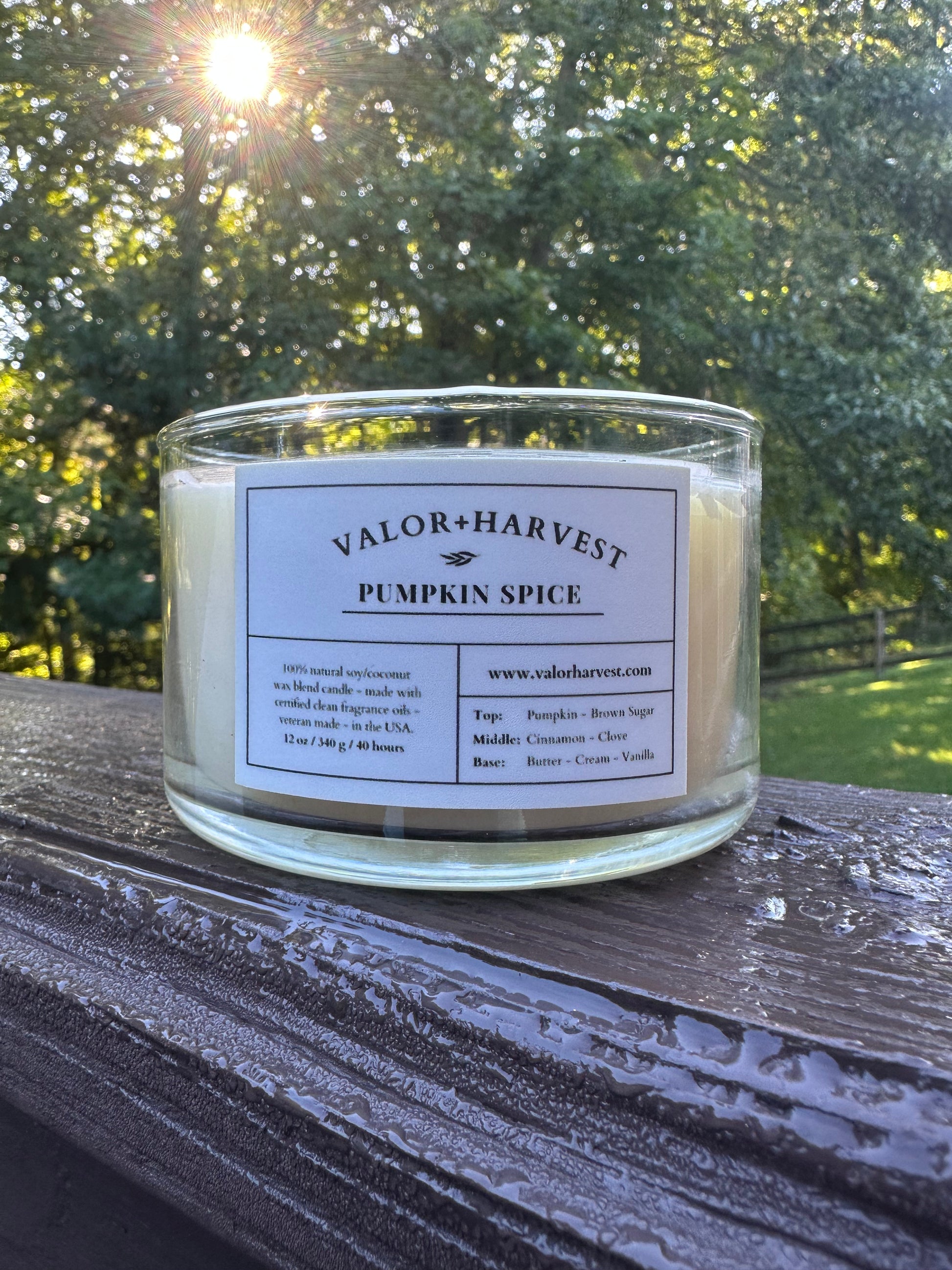 Valor+Harvest Pumpkin Spice soy wax candle in a clear glass jar outdoors at sunset.
