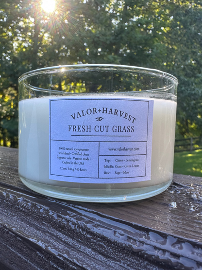 Valor+Harvest Fresh Cut Grass 12 oz coco soy wax candle on a rustic wooden surface.
