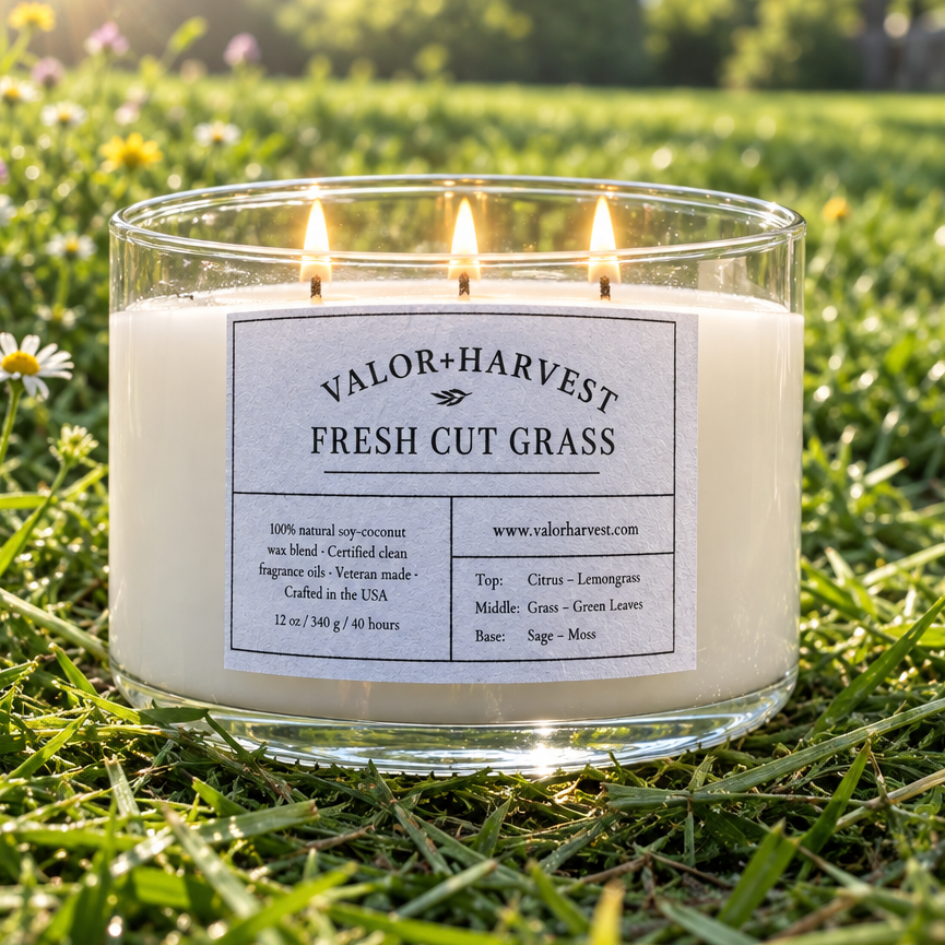 Lit Valor+Harvest Fresh Cut Grass scented coco soy wax candle in a glass jar on green grass.