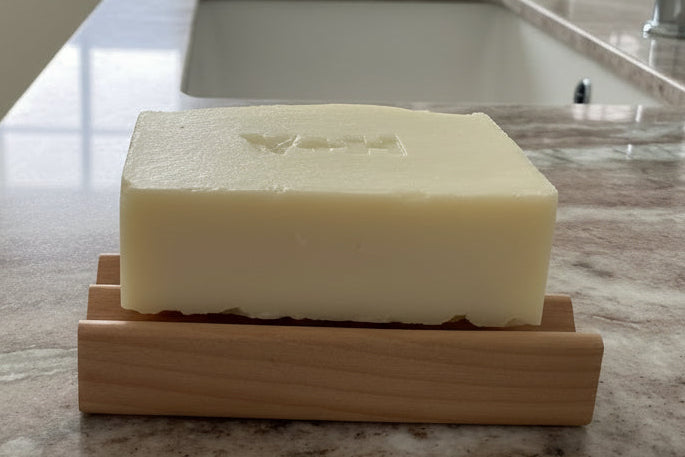 Bar of soap on a wooden soap dish on a marble countertop